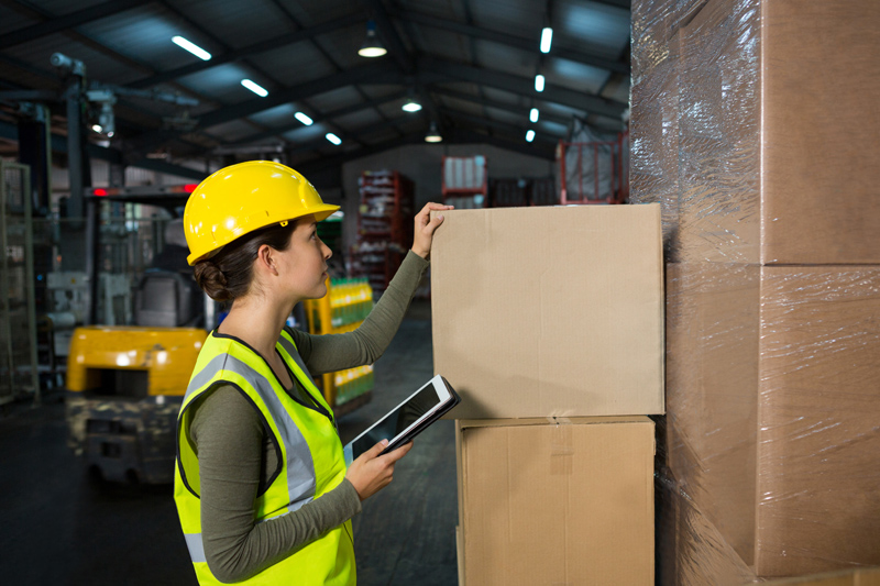Operaria en lugar de trabajo realizando control de stock en almacén.
